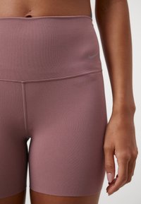 Korkeavyötäröiset malvanväriset treenishortsit, joissa on sileä ja joustava kangas, hillitty logo vyötärönauhassa ja siistit tikkauskoristeet.