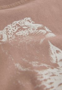 Primer plano de una cara de leopardo blanco impresa en tela texturizada rosa, mostrando detalles del pelaje y ojos.