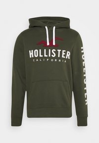 Olivgrön hoodie med en framficka, vita snoddar och "HOLLISTER CALIFORNIA" i vit och mörkröd text på bröstet.