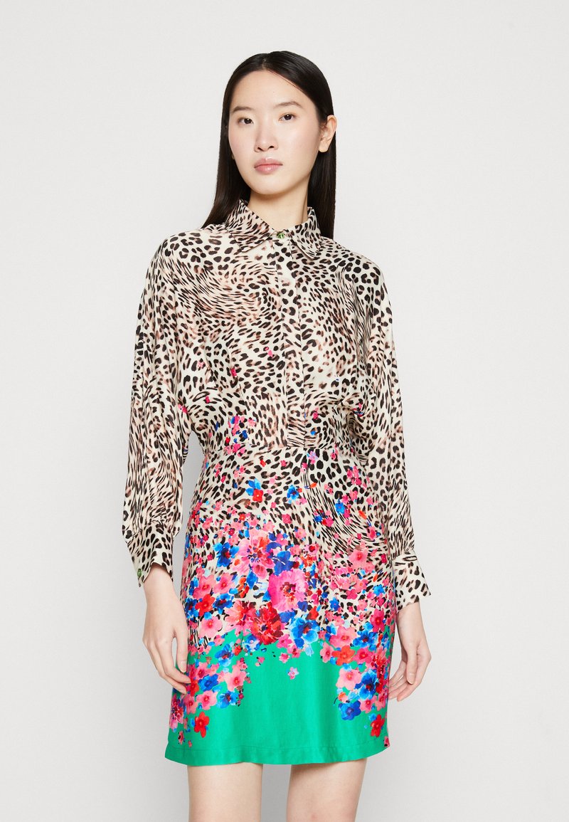 Robe à imprimé léopard avec design floral. Ourlet court et coloré avec des fleurs roses et bleues, contrasté par une base verte vibrante. Tissu lisse.