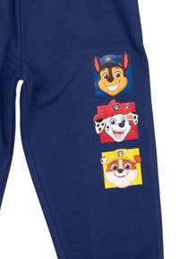 Marineblaue Jogginghosen mit drei Charakterdrucken in bunten Quadraten: ein Hund mit blauer Leine, ein weißer Hund mit Flecken und ein gelb akzentuierter Hund.