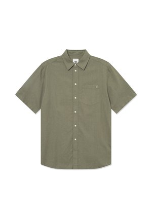 Chemise à manches courtes, de couleur olive, à boutons, fabriquée dans un tissu texturé. Elle possède une poche sur la poitrine et un logo sur le col.