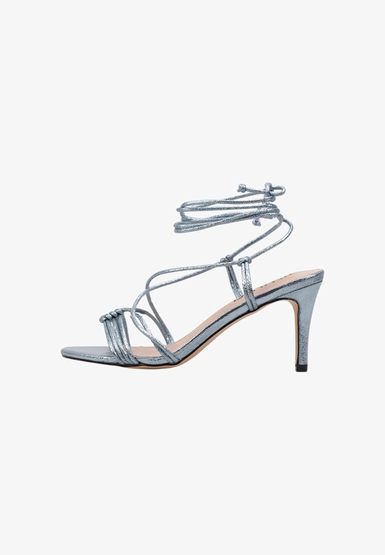 Sandale à talons hauts en métal bleu avec des fines lanières, bout ouvert et attaches à la cheville. Présente un design élégant et un talon aiguille.