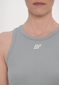 Szary prążkowany top na ramiączkach z okrągłym dekoltem i haftowanym białym logo „BP” z przodu. Gładka faktura oraz dopasowany krój.