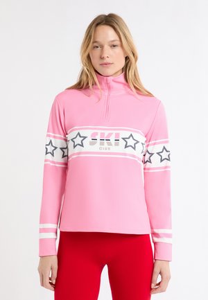 Roze ski-top met lange mouwen en een hoge kraag, met witte en zwarte sterpatronen en de tekst "SKI CLUB" over de borst. Glad materiaal.