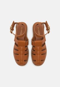 Braune Ledersandalen mit einem geflochtenen Design und einem Riemen mit Schnalle. Die Innensohle ist glatt mit geprägtem Branding und einer natürlichen Sohle.