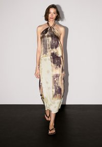 Maxi sukienka z halter neck, z abstrakcyjnymi wzorami w ziemistych odcieniach, warstwowymi fakturami i okrągłymi kropkami.