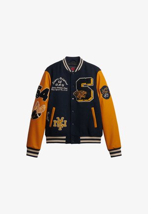 Chaqueta varsity en azul marino y naranja con parches bordados, que incluye un gran número '6', un tigre y letras. Presenta puños y cuello a rayas.