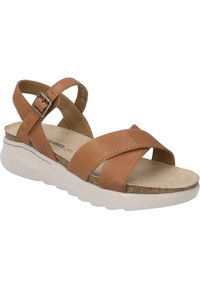 Brown leather sandal with crisscross straps, adjustable buckle, and a textured cork and white rubber sole. Flat design for comfort.