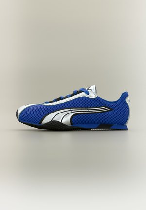 Zapatilla deportiva de malla azul y blanca con suela negra, logo de Puma blanco en el lateral y cordones azules, mostrada de perfil derecho sobre fondo neutro.