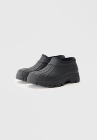 Black rubber clogs with a textured design, raised lines along the upper, and a thick, rugged sole for traction. Sturdy and water-resistant.