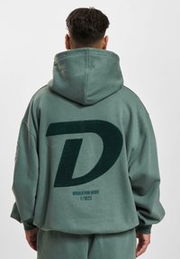 Hoodie surdimensionné vert avec un grand logo "D" noir à l'arrière, en tissu doux en mélange de coton, doté d'une capuche avec cordon de serrage et de poignets côtelés.