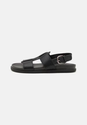 Sort læder sandal med to frontstropper, åben tå og justerbar ankelrem med sølvspænde, vist fra siden.