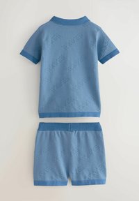 Lichtblauwe gebreide polo met korte mouwen, voorzien van een donkerblauwe kraag en zoom; bijpassende korte broek met elastische tailleband en een textuurpatroon over het geheel.