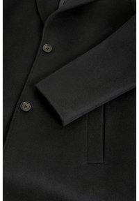 Cappotto di lana nero con due bottoni visibili, maniche dritte e una tasca a fessura sul pannello anteriore.