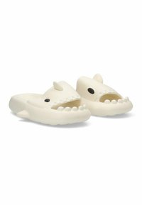 Zuecos en forma de tiburón blanco, fabricados con un material ligero y flexible; cuentan con dedos abiertos, dos aletas dorsales, y ojos negros con detalles de una sonrisa afilada.