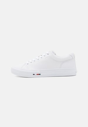 Witte sneaker van glad leer met een ronde neus, metalen oogjes en een driekleurig accent nabij de zool. Getextureerde rubberen zool.
