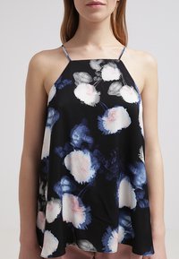 Svart ärmlös topp med blommönster i rosa, vitt och blått. Lättviktsmaterial, halterneckdesign, utsvängd passform.