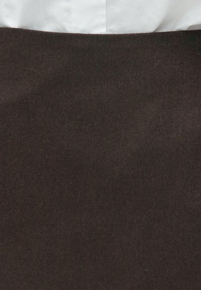 Brun stofnederdel med en blød tekstur, der har et enkelt design og en ensfarvet farve. Øverste del delvist synlig med hvidt materiale under.