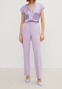 Lila satinblus med V-hals och korta ärmar, matchad med lila high-waist skräddarsydda byxor och matchande spetsiga klackskor.