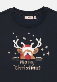 Tmavě modrá mikina s grafikou jelena s červeným nosem, bílou čepicí Santy a nápisem "Veselé Vánoce" ve třpytivých písmenech.