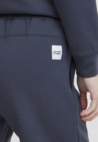 Námornícke tepláky s elastickým pásom a bočnými vreckami. Obsahujú bielu etiketu s nápisom "NORTH BEND". Hladká textúra látky.