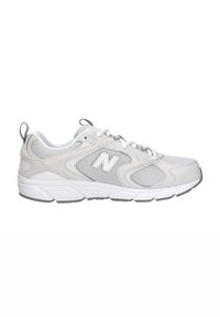 Zapatilla deportiva New Balance en gris claro y blanco con paneles de malla, cierre de cordones y suela acolchada.