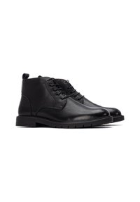 Botas de tobillo de cuero negro con acabado texturizado, punta redonda, seis pares de ojales y suela de goma. Cuenta con una tira en el talón.