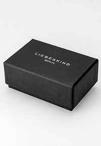 Schwarze rechteckige Geschenkbox mit texturierter Oberfläche. Auf der Oberseite befindet sich das weiße Logo "LIEBESKIND BERLIN". Einfaches Design, keine zusätzlichen Muster oder Akzente.