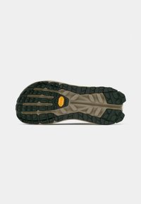 Mugurskāpes apavu ārējā zole ar raupju gumijas zīmējumu tumši zaļā krāsā, kontrastējoša gaiši brūna starpzole un Vibram logo.