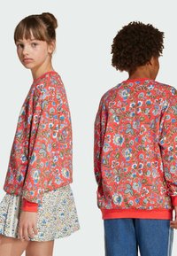 Svetrová mikina s dlhými rukávmi, červeným kvetinovým vzorom, rebrovanými manžetami a okrúhlym výstrihom. Skombinovaná s vzorovanou sukňou a denimovými šortkami.