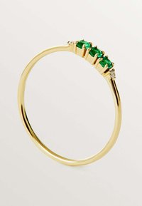 Anillo de oro con tres piedras verdes engastadas en ajustes de garras, con una pequeña piedra de acento. La banda es lisa y pulida.