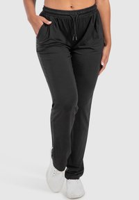 Zwarte joggingsbroek gemaakt van zacht materiaal, met een elastische tailleband met een trekkoord, zijzakken en een relaxed fit.