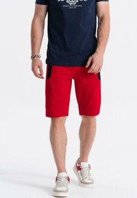 Rode shorts van een katoenmix met een soepele textuur, voorzien van zwarte zijzakken. Draag ze met een marineblauw T-shirt en stijlvolle sneakers.