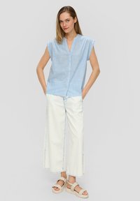 Lichtblauwe gestreepte korte mouw shirt met een V-hals en knoopsluiting, gecombineerd met brede witte denim broeken en lichtbeige plateau-sandalen.
