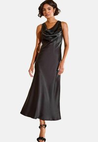 Černé saténové šaty s drapovaným výstřihem a bezramenným designem, sahající až po kotníky. Mají hladkou texturu a jednoduchou siluetu.