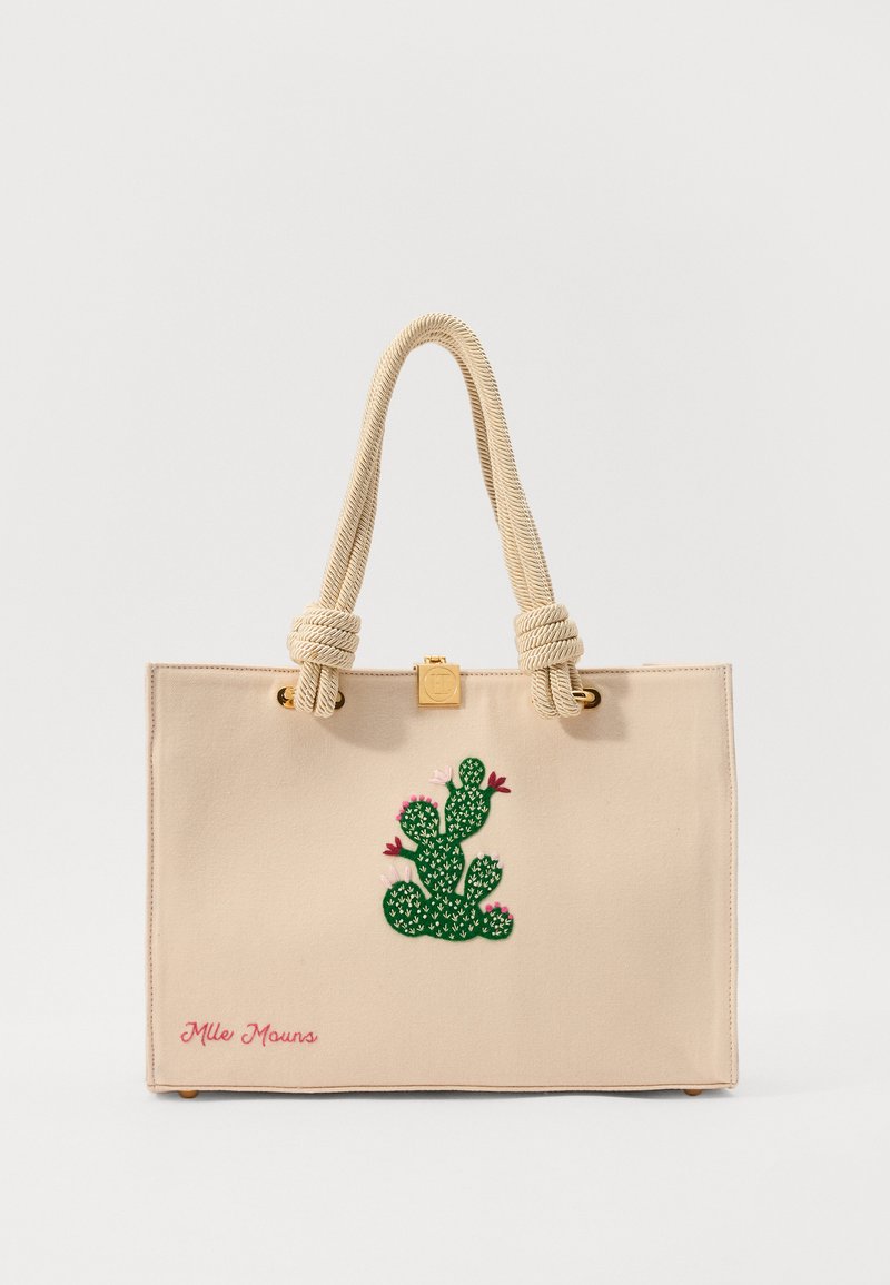 Beige canvas tote bag with a green cactus embroidery and pink flower accents, featuring rope handles and a gold hardware detail.