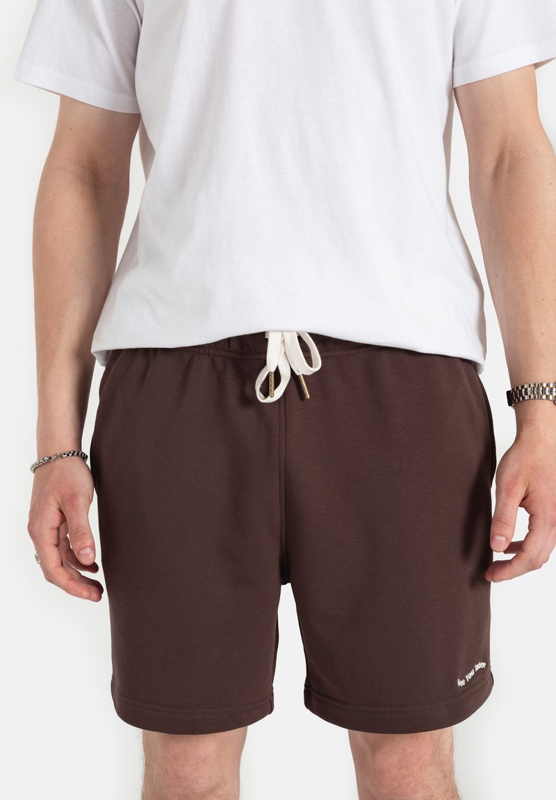 Brązowe szorty wykonane z miękkiego materiału, z elastycznym pasem w talii i białym sznurkiem, oraz małym napisem na dołach.