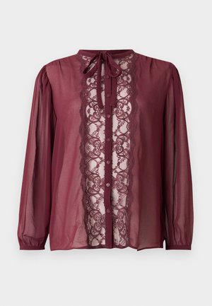 Blouse bordeaux à manches longues, avec un panneau en dentelle sur le devant, fermeture à boutons et détail de nouage au col. Tissu transparent avec épaules froncées.