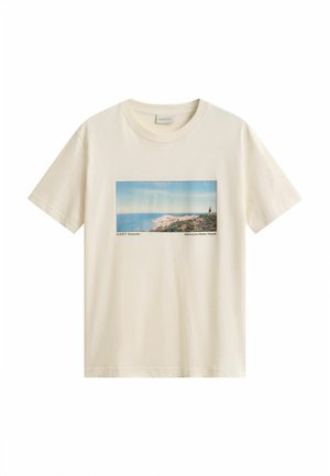 Beige short-sleeve t-shirt with a rectangular seaside landscape print, showing ocean, cliffs, and a lighthouse on the right side.