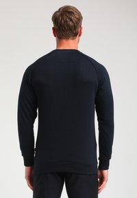 Felpa blu navy con maniche lunghe, texture a coste, motivo diagonale sul retro e scollo a girocollo, che mette in evidenza un design aderente.