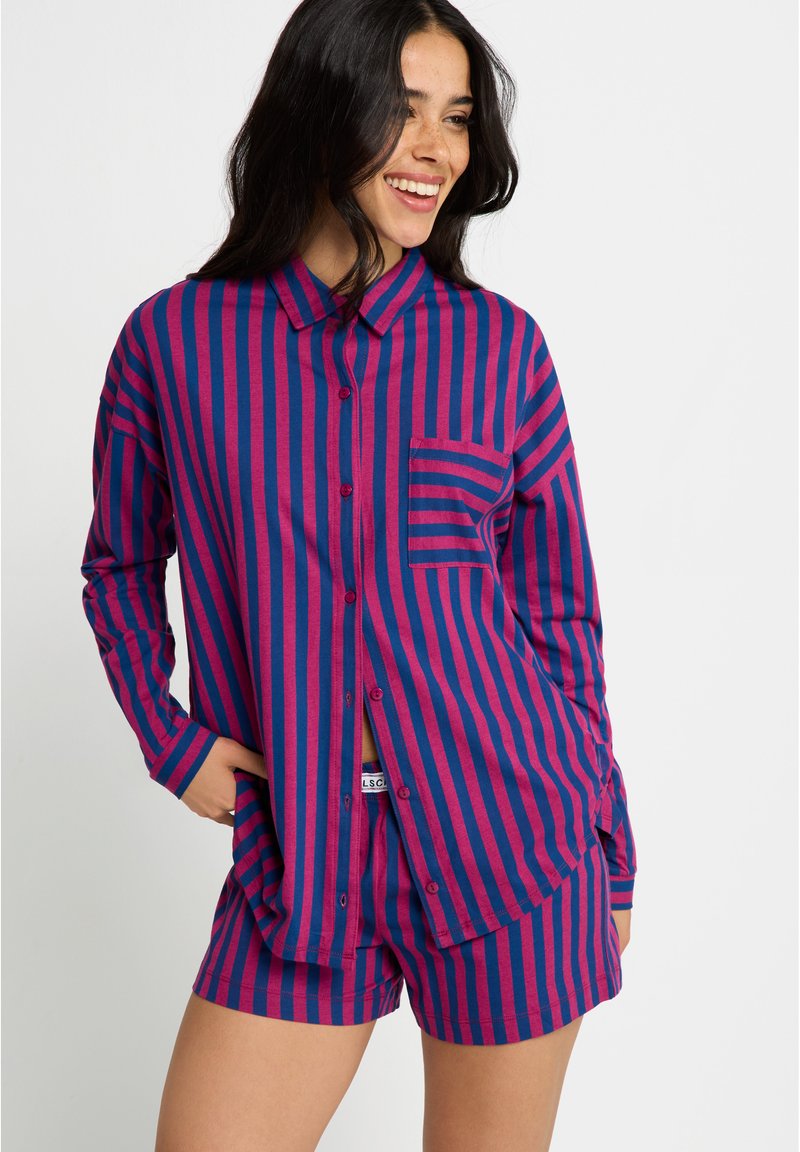 Conjunto de pyjama de algodão em riscas verticais roxas e azuis, com uma camisa de botão com colarinho e bolso no peito, acompanhada de calções a condizer.