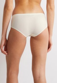 Crème-kleurige dames hipster onderbroek van gladde stof, met een naadloos ontwerp en een middelhoge tailleband.