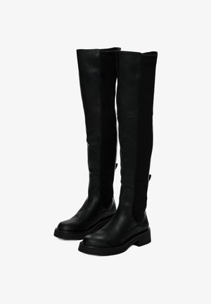 Czarne botki za kolano z gładkiej skóry, z prążkowanymi panelami tekstylnymi, płaskimi podeszwami i szerokim, sztywnym kształtem.