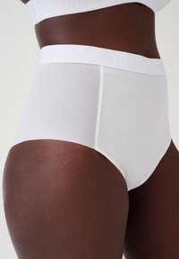 Hoge taille witte onderbroek van glad, rekbaar materiaal, met een zachte elastische tailleband met een reliëf logo detail.