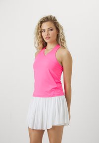 Rosa trenings tank topp med kryssryggdesign, kombinert med en plisséert hvit skort, som har lett og pustende stoff.