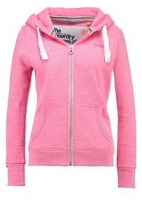 Rosa zip-up hoodie i mjukt material, med huva, vita dragsnören, framskjutna fickor och ribbade ärmslut. Logotyp tryckt på insidan.