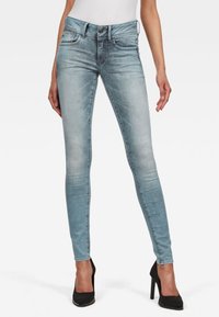 Světle modré skinny džíny s jemnou denimovou texturou, obsahující zapínání na knoflík a zip, přední kapsy a jemné detaily vyblednutí.