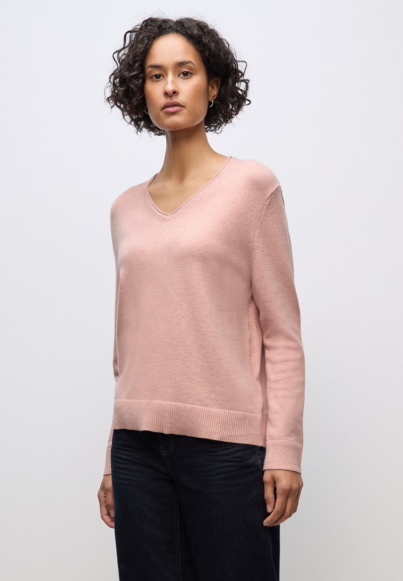 Maglione rosa chiaro lavorato a maglia con scollo a V, maniche lunghe e orlo a coste. Texture liscia, vestibilità rilassata e dettagli di design minimalisti.