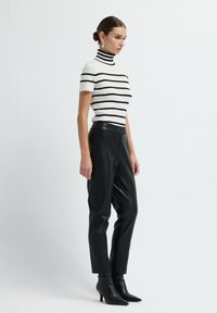 Zwart-wit gestreept ribgebreid coltruitje gecombineerd met hoge zwarte leren broek en spitse zwarte enkellaarsjes.